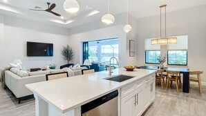 Una cocina moderna con una isla central, armarios blancos e iluminación colgante.