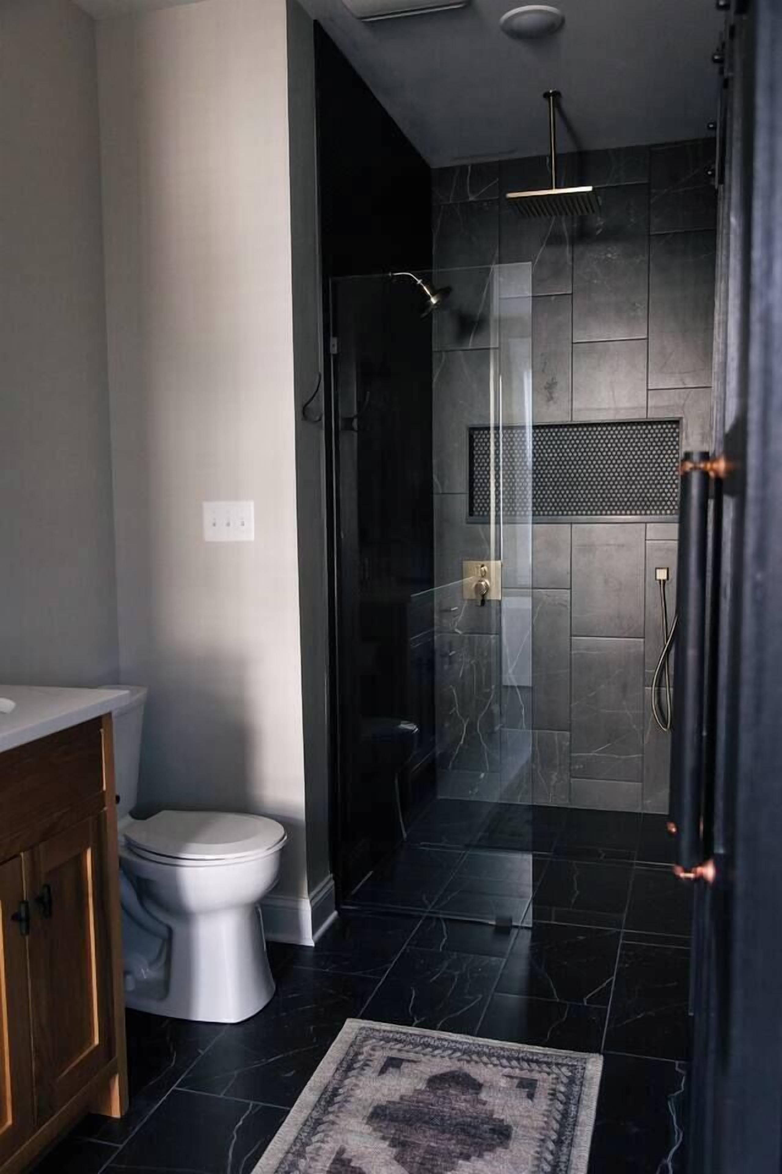 Un baño moderno con inodoro, ducha y cabina de ducha acristalada.