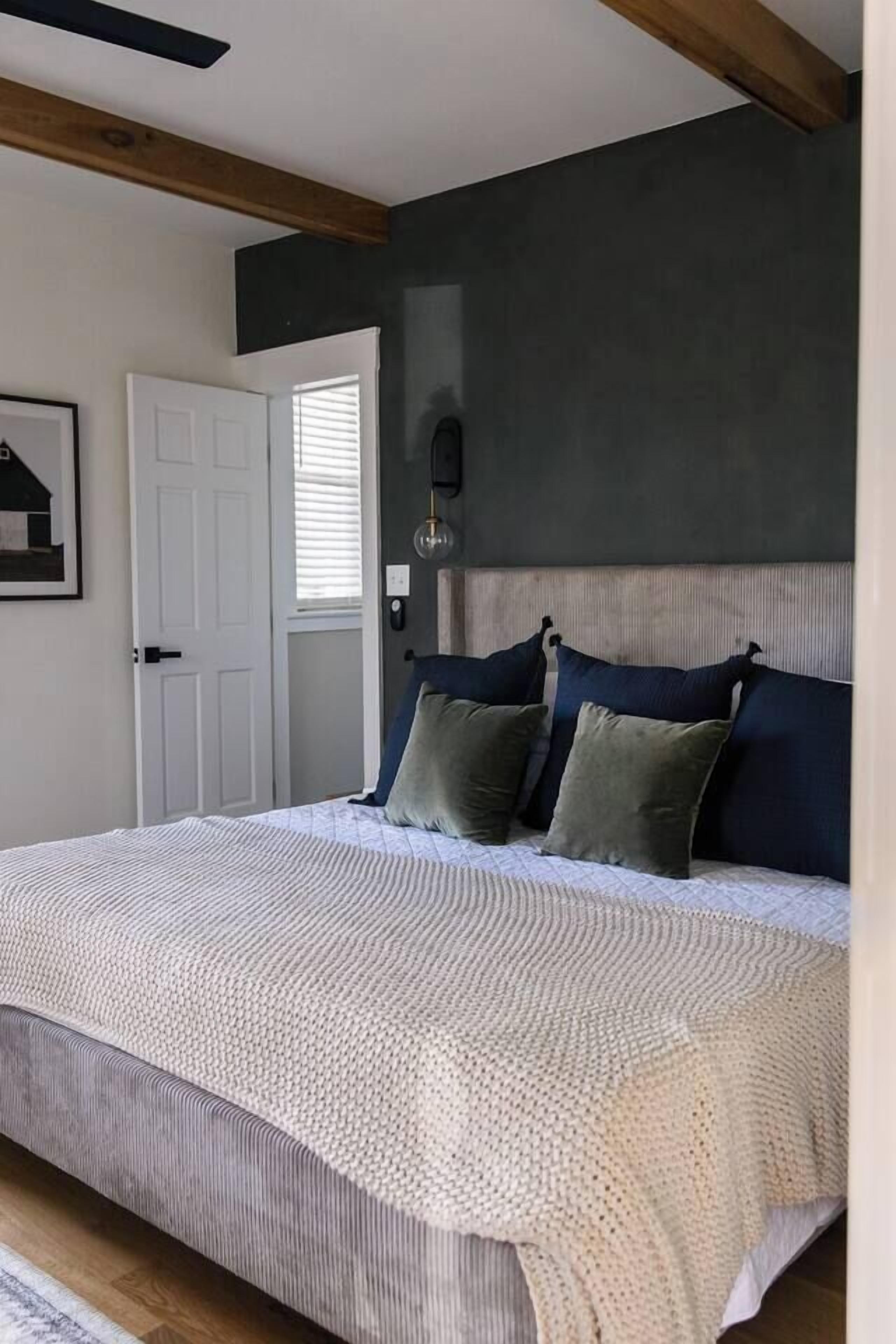 Une chambre à coucher avec un grand lit, une tête de lit sombre et une porte blanche.