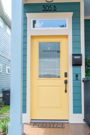 A yellow door with a window, a mailbox, and a doormat. - The Mangrove Suite. Newly Built, Upscale, Central (Gainesville)