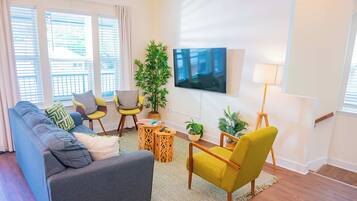 Una sala de estar moderna con un sofá gris, un sillón amarillo y un televisor de pantalla plana montado en la pared.