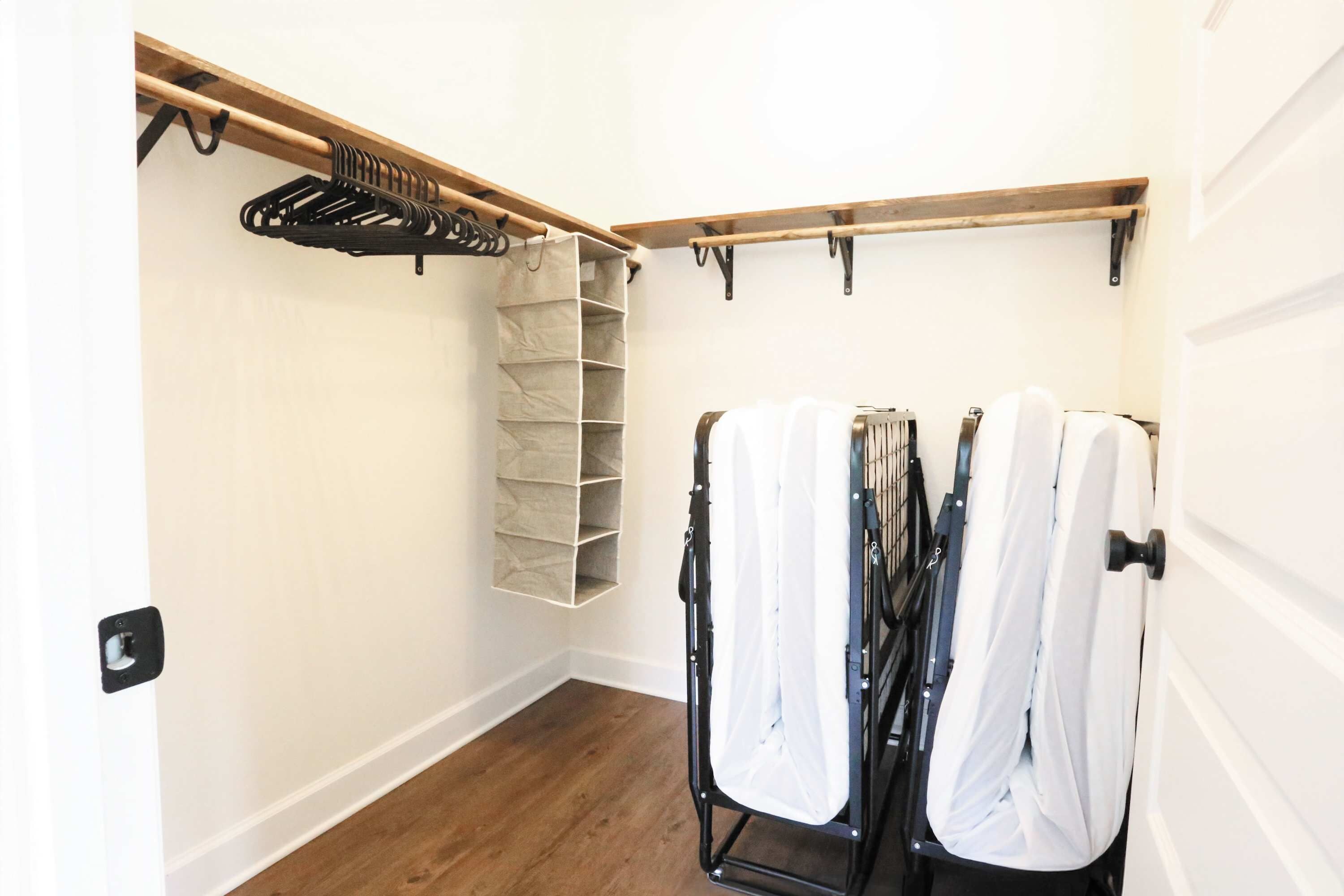 Un dressing accessible sans porte, avec un banc en bois, un étendoir et un meuble de rangement.