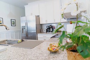 A modern kitchen with white cabinets, stainless steel appliances, and a granite countertop. - The Botanical Suite. Newly Built, Upscale, Central (Gainesville)