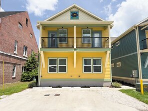 A two-story yellow building with a balcony, numbered 309, and a brick building to the left. - The Botanical Suite. Newly Built, Upscale, Central (Gainesville)