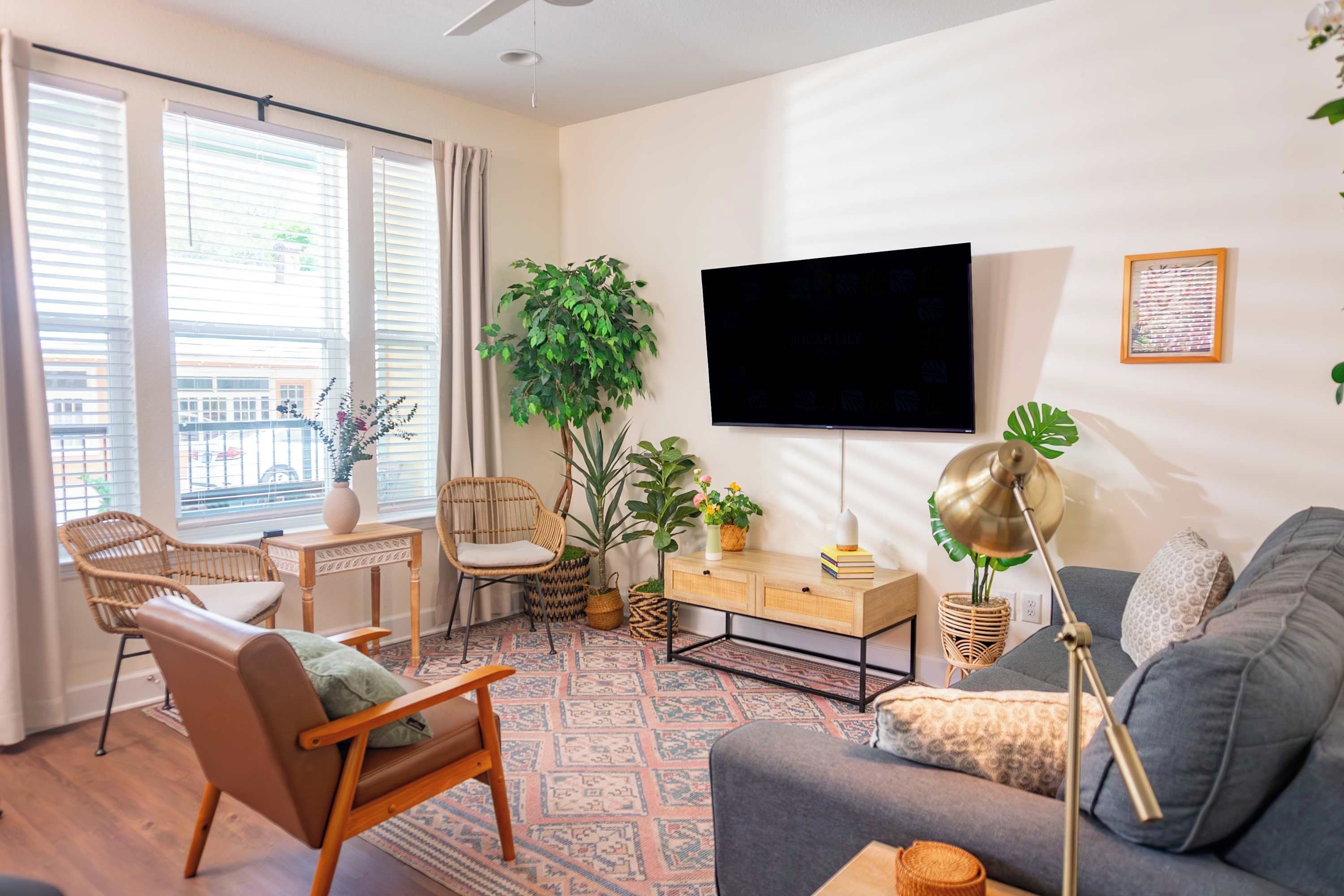 Un salon avec un canapé, un fauteuil, une télévision et des plantes.