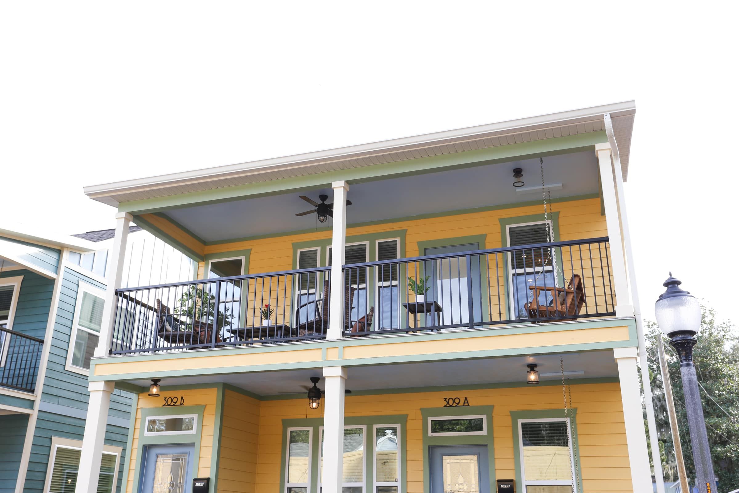 A two-story building with a balcony, numbered 309A, featuring a porch with a railing and a street lamp.