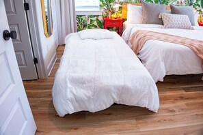 A bedroom with two beds, a red nightstand, and a window with a view of greenery. - The Royal Crane Suite, New Build, Upscale, Central (Gainesville)