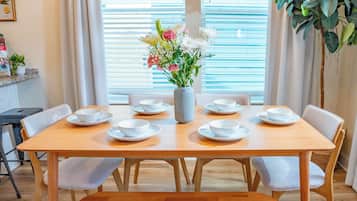 Et spisebord med hvide tallerkener og skåle, en vase med blomster og en bænk.