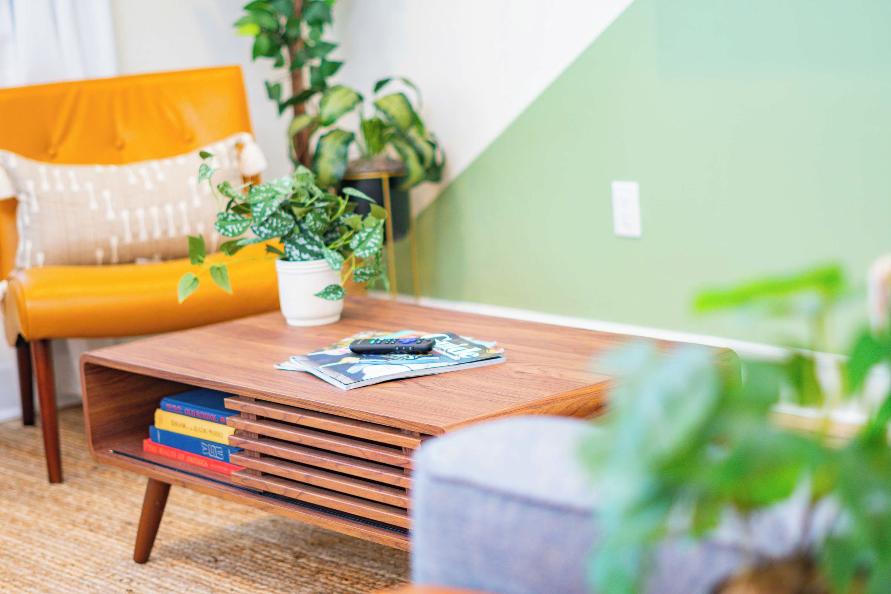 Un salon chaleureux avec une table basse en bois, un fauteuil jaune et une plante en pot.