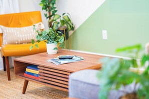 A cozy living room with a wooden coffee table, a yellow armchair, and a potted plant. - The Royal Crane Suite, New Build, Upscale, Central (Gainesville)