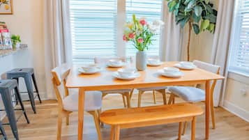 A dining area with a wooden table set for four, surrounded by chairs.