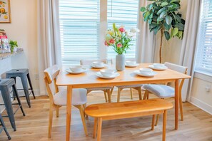 A dining area with a wooden table set for four, surrounded by chairs.