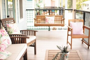 A wooden porch with two wooden chairs and a bench, each with a cushion. - The Lotus Suite. Newly Built, Upscale, Central (Gainesville)