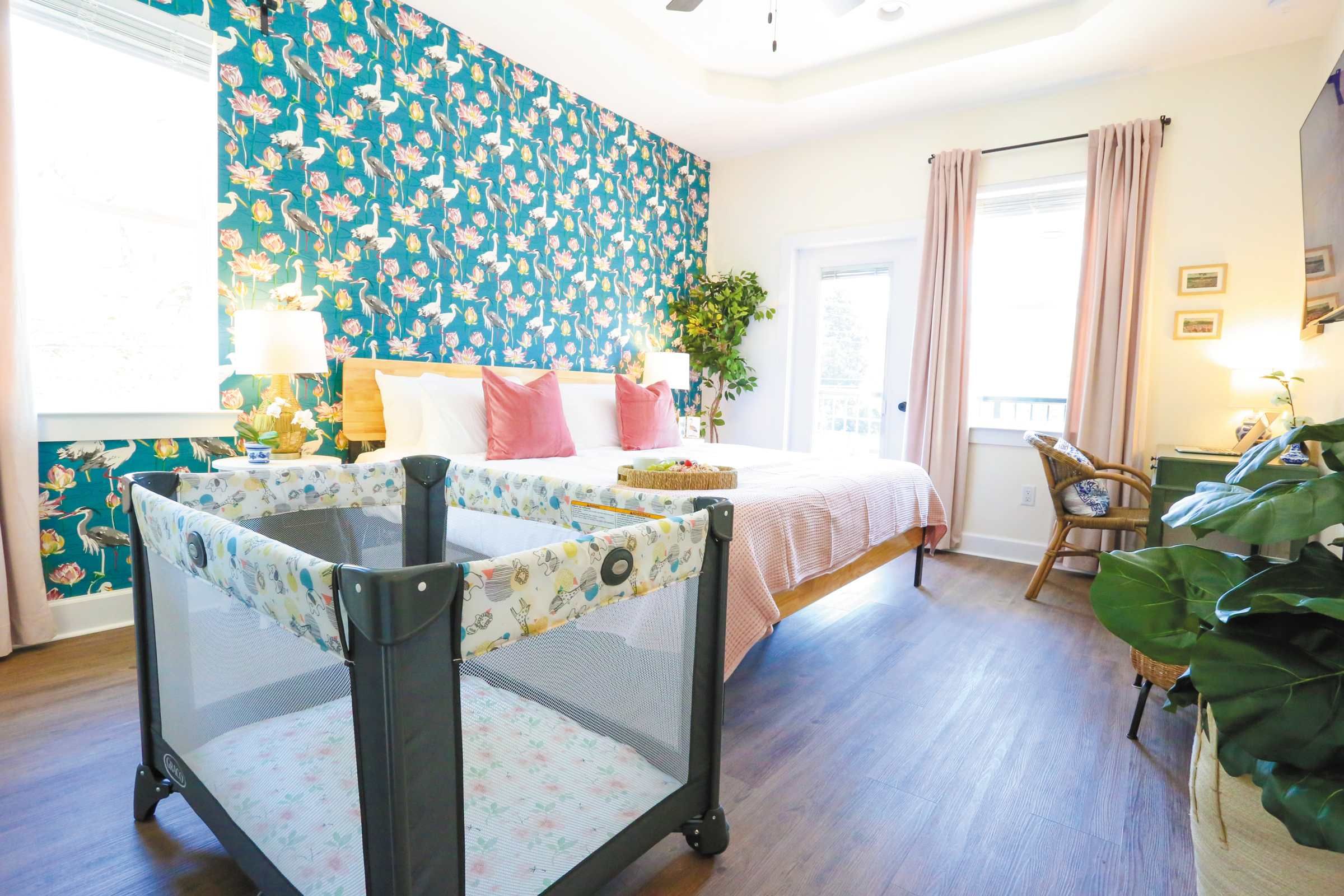 A bedroom with a bed, a chair, a table, and a large plant.