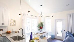 Een moderne keuken met granieten aanrechtbladen, een roestvrijstalen spoelbak en hanglampen.