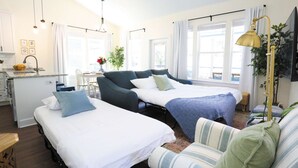 Een moderne hotelkamer met twee bedden, een zithoek en een kitchenette.