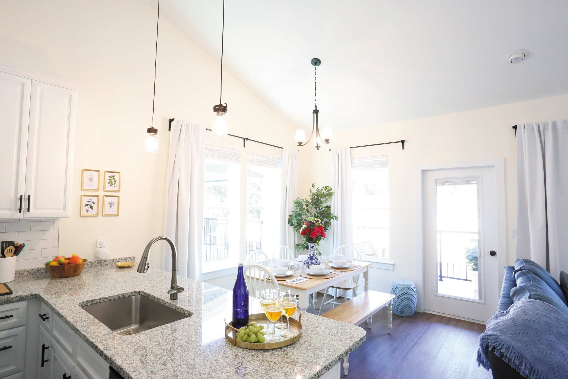 A modern kitchen with granite countertops, a stainless steel sink, and pendant lighting.
