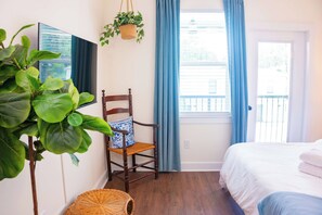 A bedroom with a bed, a chair, a hanging plant, and a window with curtains. - The Lotus Suite. Newly Built, Upscale, Central (Gainesville)
