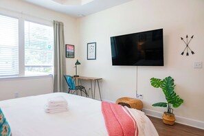 A bedroom with a bed, a desk, a television, and a plant. - The Prairie Suite. Newly Built, Upscale, Central (Gainesville)