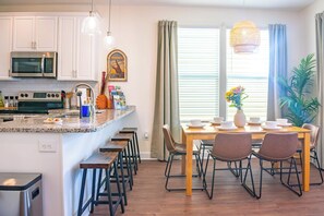 A modern kitchen with white cabinets, a built-in microwave, and a stainless steel stove. - The Prairie Suite. Newly Built, Upscale, Central (Gainesville)