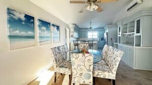 A dining area with patterned chairs, a ceiling fan, and a view of the ocean through large windows. - 3bd/2ba Villa in the Bight - Alta 3 (The Bight Settlement)
