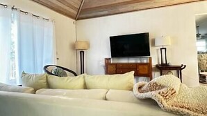 A room with a sofa, a television on a wooden cabinet, and a lamp. - 3bd/2ba Villa in the Bight - Alta 3 (The Bight Settlement)