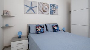 A bedroom with a bed, two bedside tables, a nightstand, and wall art. - Casa Marisa by Wonderful Italy (Golfo Aranci)