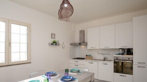 A modern kitchen with white cabinets, a gas stove, and a built-in oven. - Casa Marisa by Wonderful Italy (Golfo Aranci)