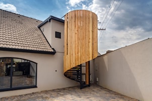 A modern house with a spiral staircase and a wooden cylindrical structure.