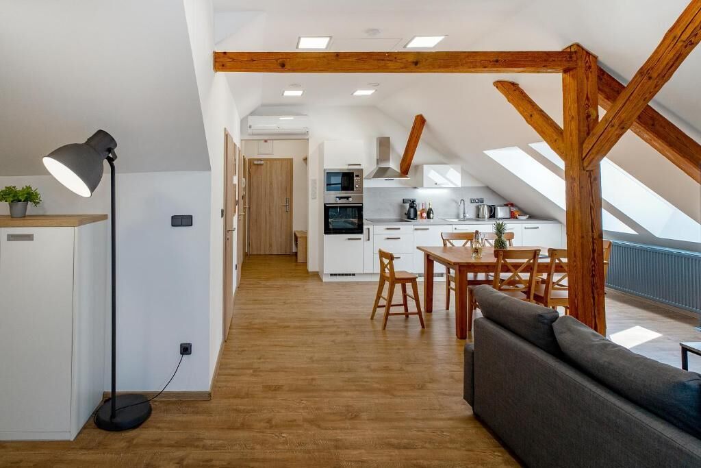Cozinha moderna com armários brancos, área de refeições com móveis de madeira e teto estilo loft com vigas aparentes.