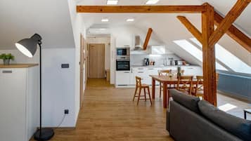 Cozinha moderna com armários brancos, área de refeições com móveis de madeira e teto estilo loft com vigas aparentes.