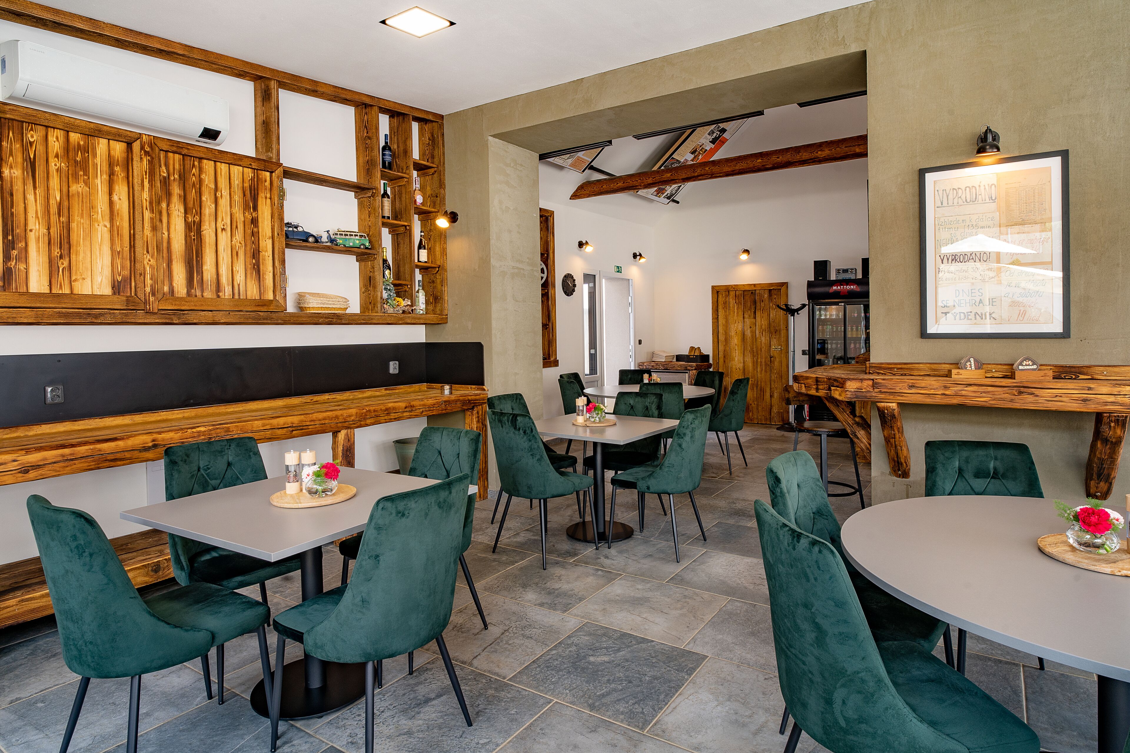 Un restaurante con paneles de madera, sillas tapizadas en verde y suelo de baldosas.