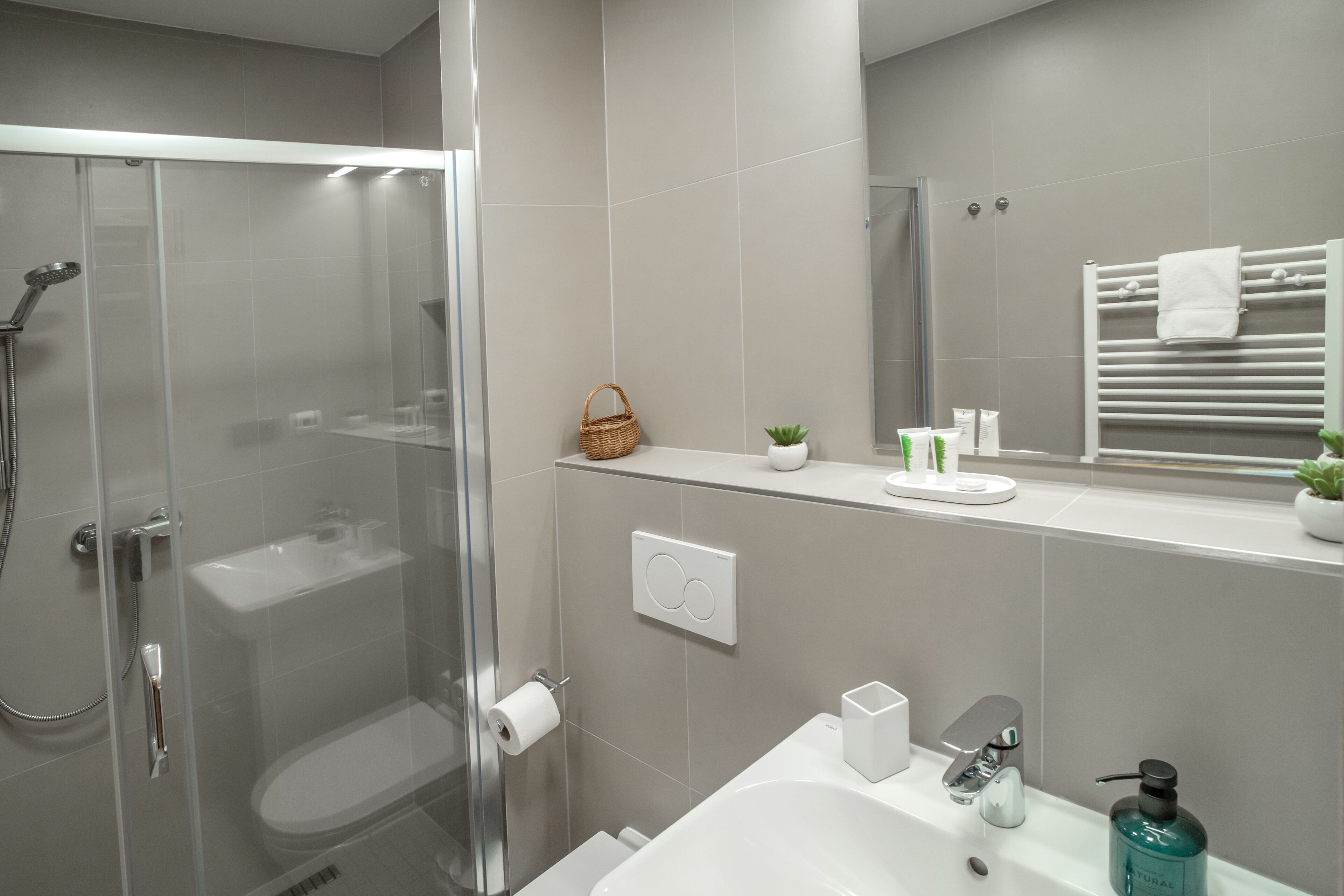 A modern bathroom with a glass-enclosed shower, a white sink, and a mirror above the sink.