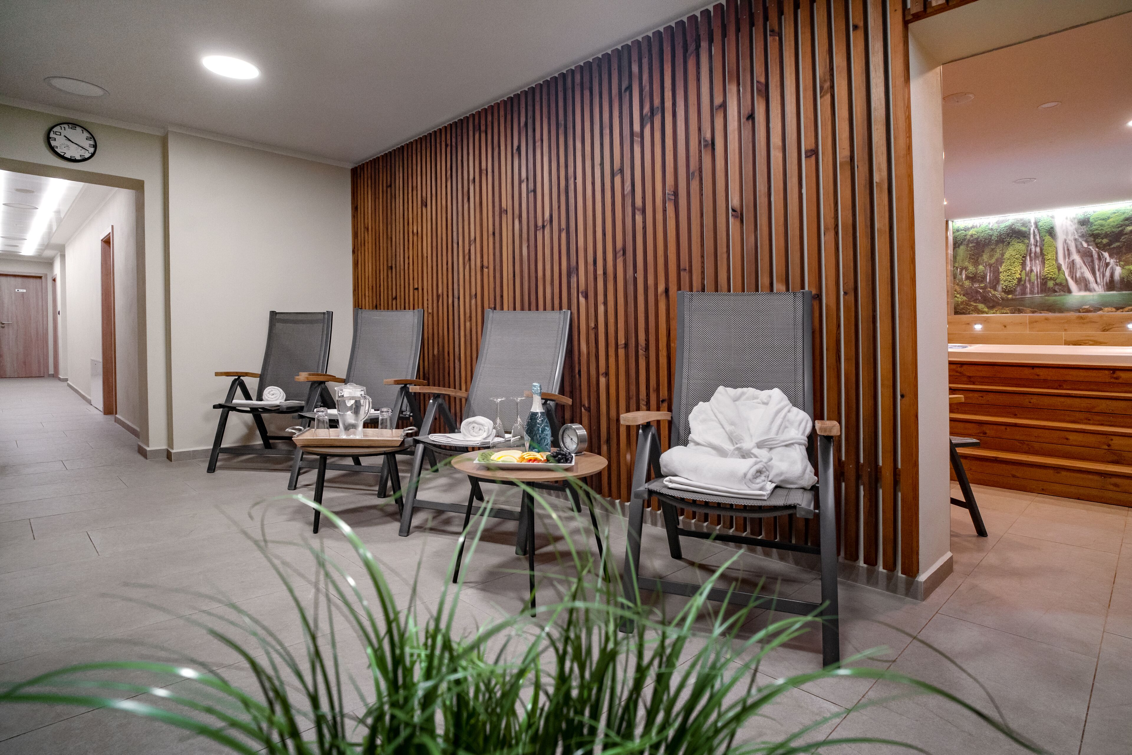 A modern reception area with wooden paneling, a reception desk, and a large wall-mounted screen displaying a waterfall.