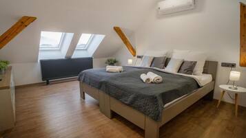 A bedroom with a bed, skylight, radiator, and a small bedside table with a lamp.