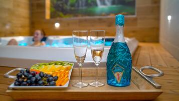 A tray with a bottle of champagne, two glasses, and a fruit platter on a wooden table.