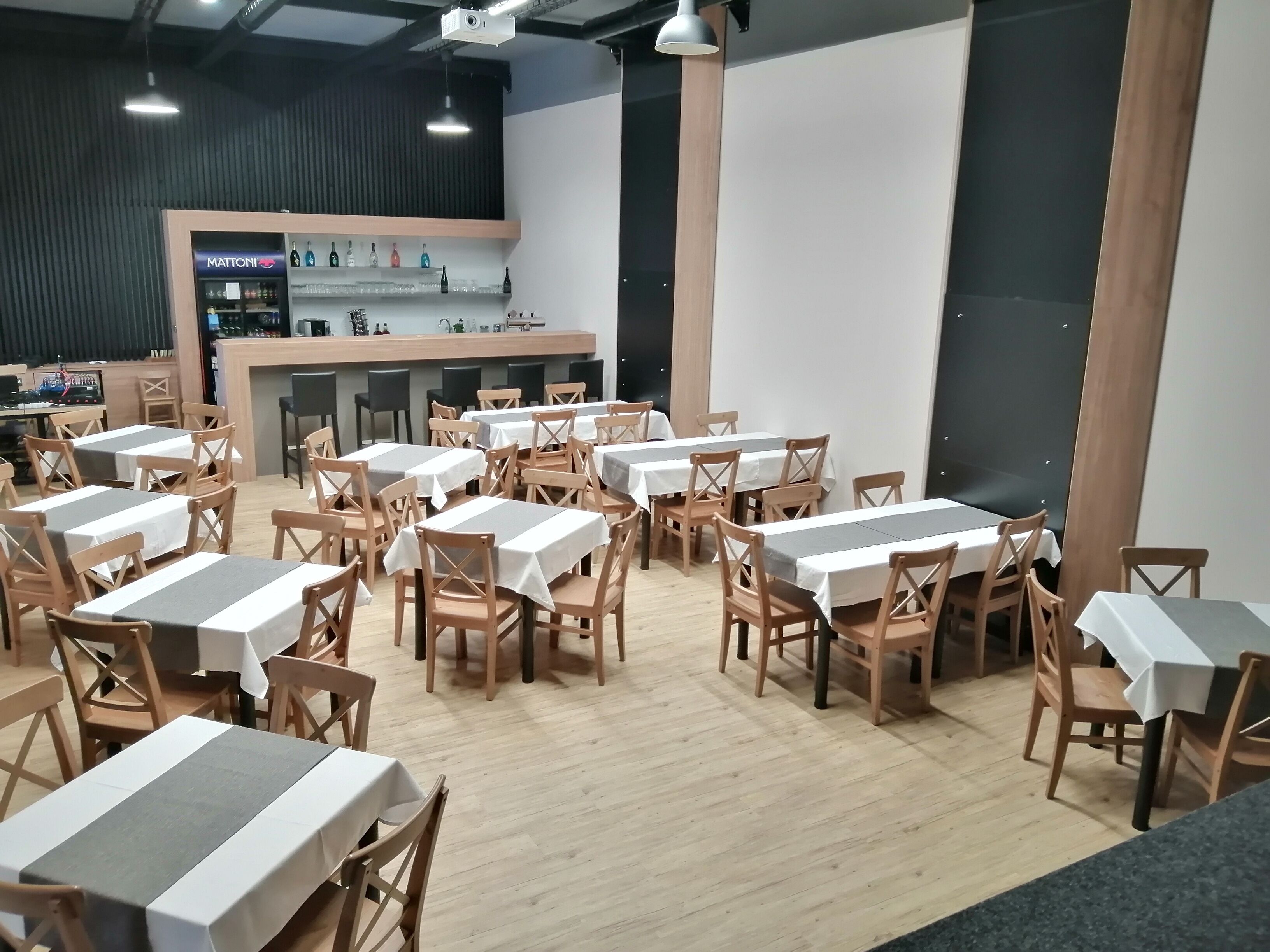 Un restaurant doté de nombreuses tables et chaises, d’un bar avec un comptoir et d’une grande fenêtre.