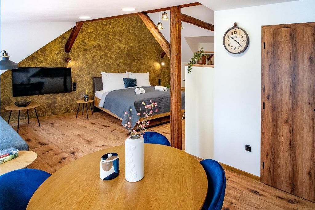 A bedroom with a sloped ceiling, a bed, a TV, and a wooden door.