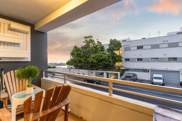 Ein Balkon mit Blick auf eine Straße, einem Blumentopf und einem Tisch mit Stühlen.