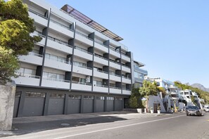 Ein mehrstöckiges Gebäude mit Balkonen, einer Garagentür und einem wolkenlosen Himmel.