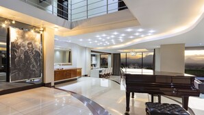 A spacious living area with a piano, a dining table, and a large artwork on the wall. - Baronetcy Kings Villa (Cape Town)