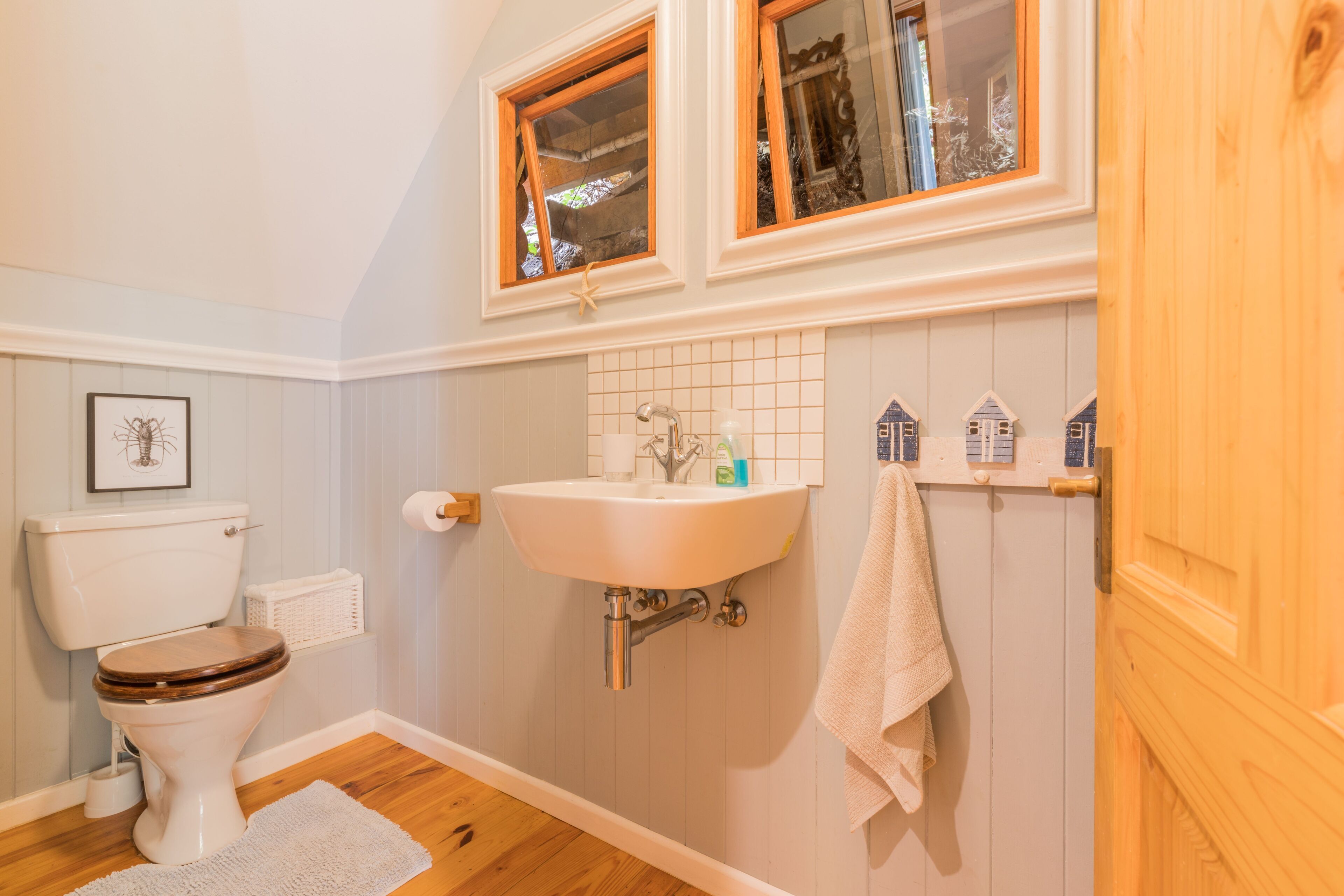 Een badkamer met toilet, wastafel en houten vloer.