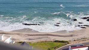 A coastal view with a beach, rocky shoreline, and buildings in the foreground.