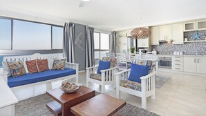 A modern living room with a white sofa, blue cushions, and a wooden coffee table.