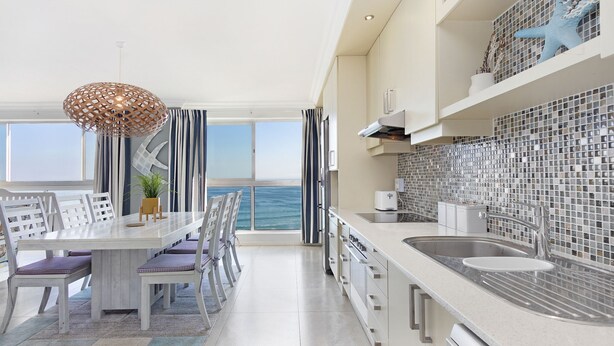 A modern kitchen with a large island, a view of the sea, and a dining area with a view.