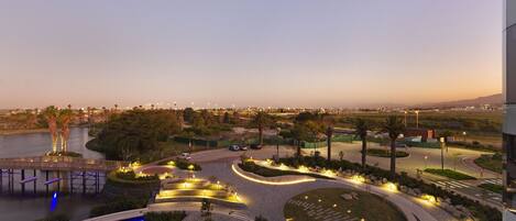 A landscaped urban area with a curved pathway, a small water feature, and a bridge over a body of water.