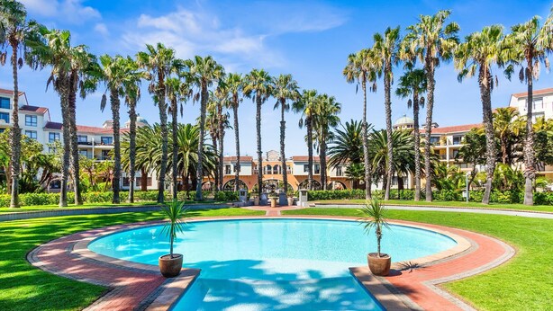 A swimming pool surrounded by palm trees and a building with a dome.