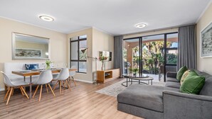 A modern living room with a dining area, large windows, and a balcony.