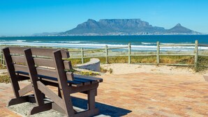 A bench overlooking a beach with a view of a mountain and ocean.