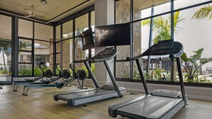 A gym with treadmills, rowing machines, and weights.